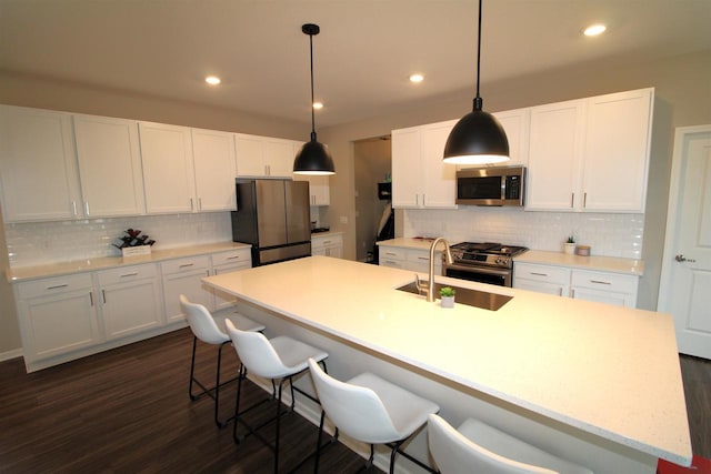 1677 Liatris Dr, Sun Prairie, WI 53590 - kitchen featuring a breakfast bar area, stainless steel appliances, white cabinetry, backsplash, and a center island with sink