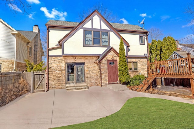 view of front of house with fence, a gate, stucco siding, and stone siding