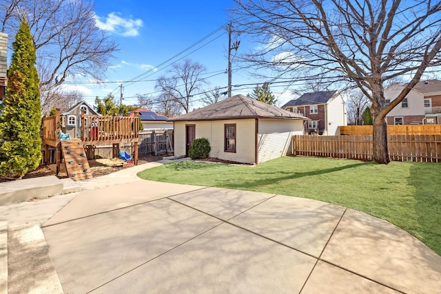 rear view of property featuring a lawn, fence, an outdoor structure, a playground, and a patio