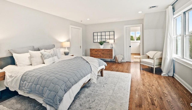 bedroom with baseboards, recessed lighting, wood finished floors, and visible vents
