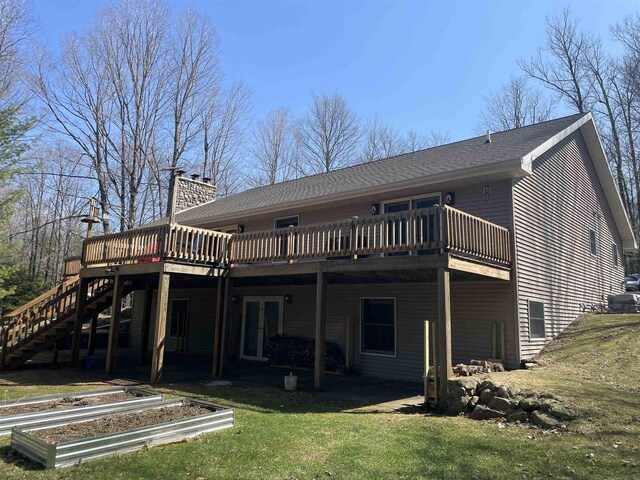 W9831 Miscauno Island Ln, Daggett, MI 49821 - back of property featuring a wooden deck, a vegetable garden, stairway, a chimney, and a lawn