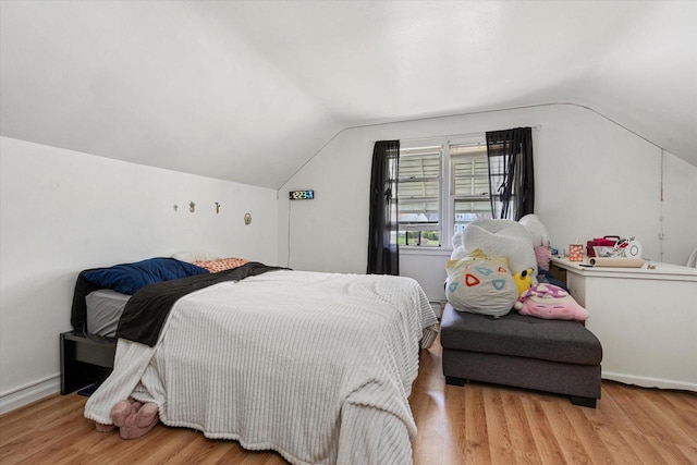 bedroom with vaulted ceiling, baseboards, and wood finished floors