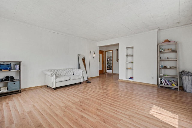 unfurnished room with baseboards, light wood-type flooring, built in shelves, and ornamental molding