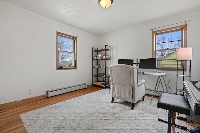 home office featuring a baseboard heating unit, wood finished floors, and a wealth of natural light