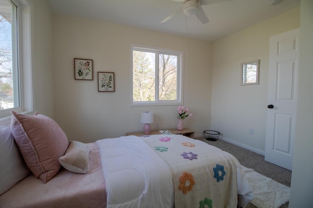 carpeted bedroom featuring ceiling fan, baseboards, and multiple windows