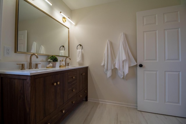 full bathroom featuring baseboards, a sink, and double vanity