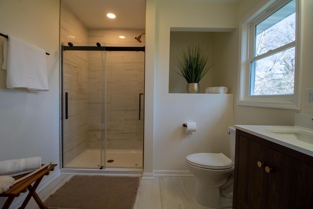 bathroom featuring toilet, a stall shower, baseboards, recessed lighting, and vanity