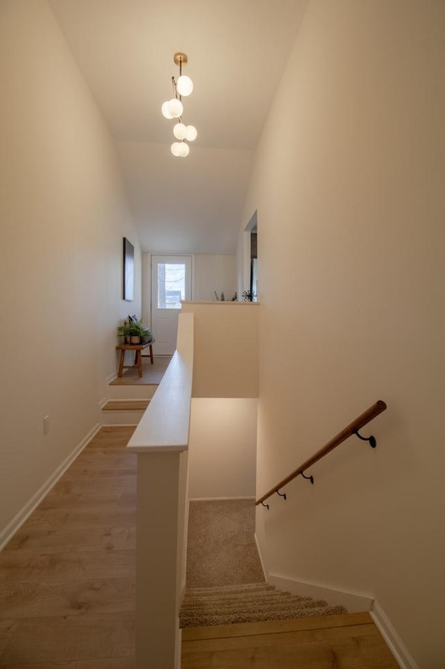 stairway with baseboards, lofted ceiling, and wood finished floors