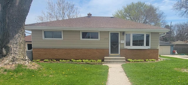 bungalow-style house with a chimney, brick siding, entry steps, roof with shingles, and a front lawn