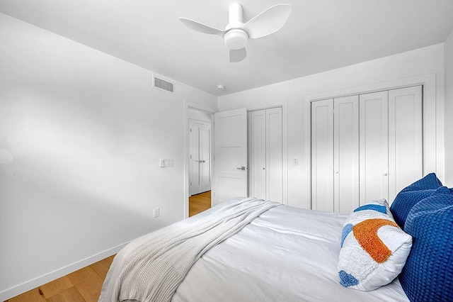 8226 Scott Rd, Cross Plains, WI 53528 - bedroom with two closets, a ceiling fan, baseboards, wood finished floors, and visible vents