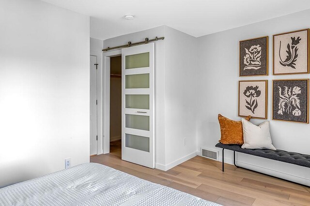 8226 Scott Rd, Cross Plains, WI 53528 - bedroom featuring baseboards, visible vents, a barn door, and wood finished floors