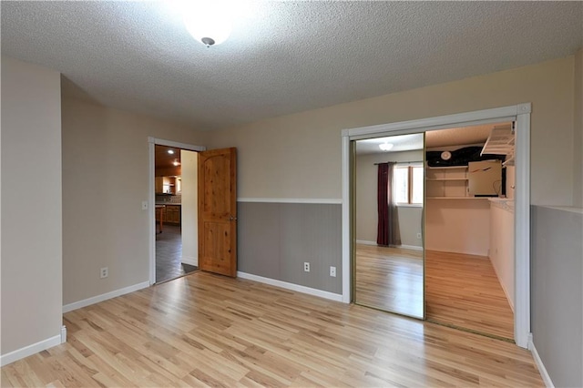 W3803 Church Rd, Sarona, WI 54870 - unfurnished bedroom featuring baseboards, a textured ceiling, light wood finished floors, and a closet