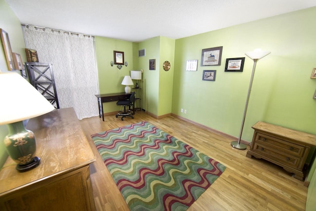 sitting room with baseboards, wood finished floors, and visible vents