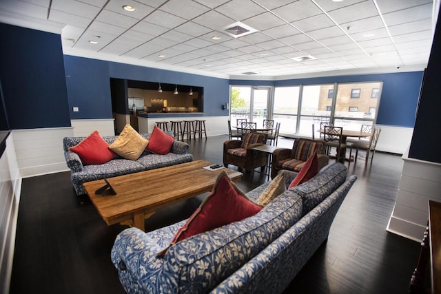 living area featuring wood finished floors, a paneled ceiling, a wainscoted wall, and visible vents