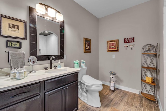 bathroom with wood finished floors, toilet, vanity, and baseboards