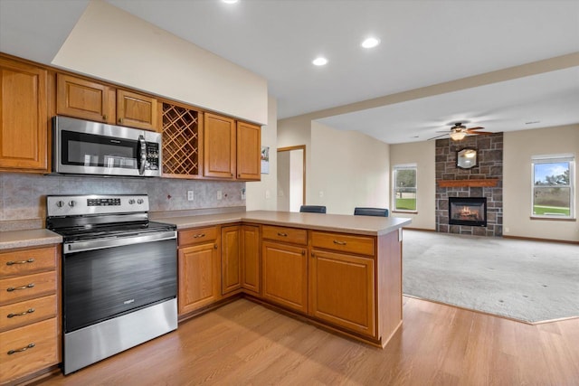 kitchen with light countertops, a peninsula, appliances with stainless steel finishes, and light wood-style flooring