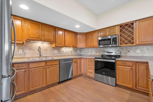 kitchen featuring light countertops, stainless steel appliances, light wood-type flooring, and a sink