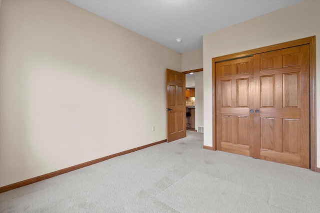 unfurnished bedroom with baseboards, carpet floors, and a closet