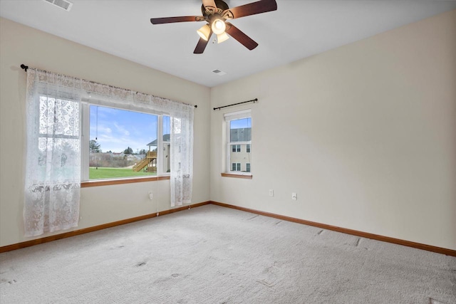 empty room featuring carpet floors, visible vents, a ceiling fan, and baseboards