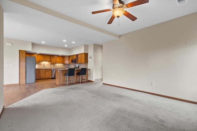 unfurnished living room featuring recessed lighting, ceiling fan, light carpet, and baseboards