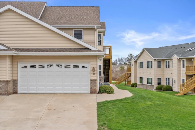 exterior space with a yard, stairs, roof with shingles, concrete driveway, and an attached garage
