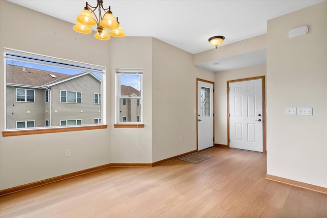 foyer featuring wood finished floors, a chandelier, and baseboards