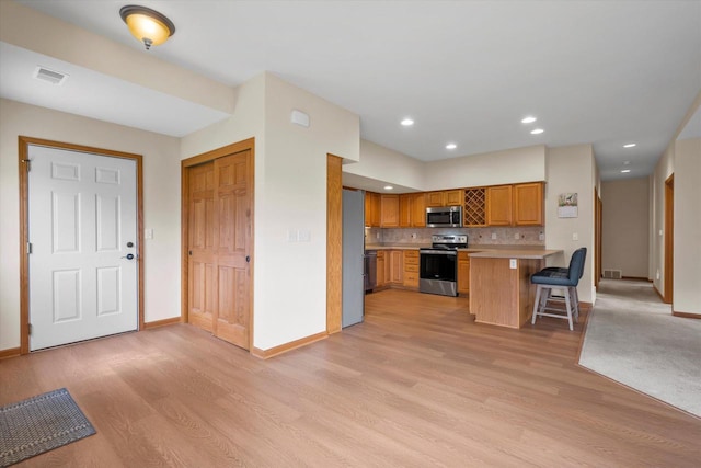 kitchen with light wood-type flooring, visible vents, appliances with stainless steel finishes, and baseboards