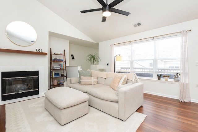 living room featuring a tiled fireplace, a ceiling fan, visible vents, vaulted ceiling, and wood finished floors