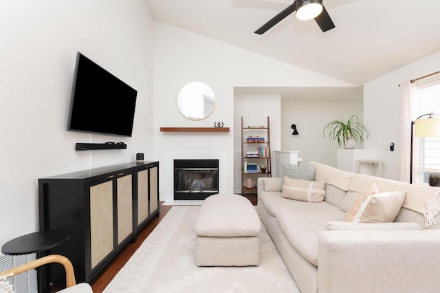 living room featuring a glass covered fireplace, ceiling fan, dark wood-style flooring, and vaulted ceiling