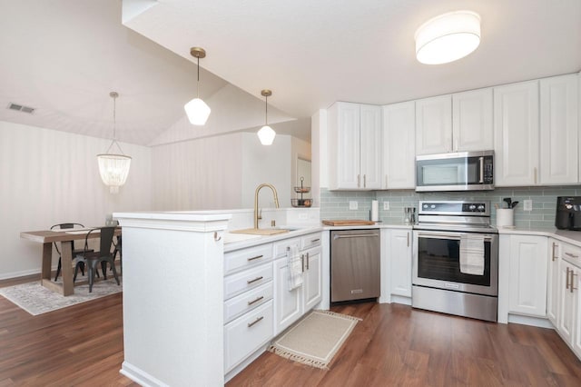 kitchen with a sink, stainless steel appliances, visible vents, a peninsula, and light countertops