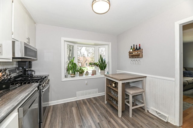 kitchen with visible vents, white cabinets, dark wood-style flooring, and stainless steel appliances