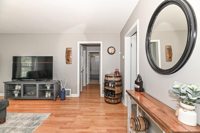living room with visible vents, light wood finished floors, and baseboards