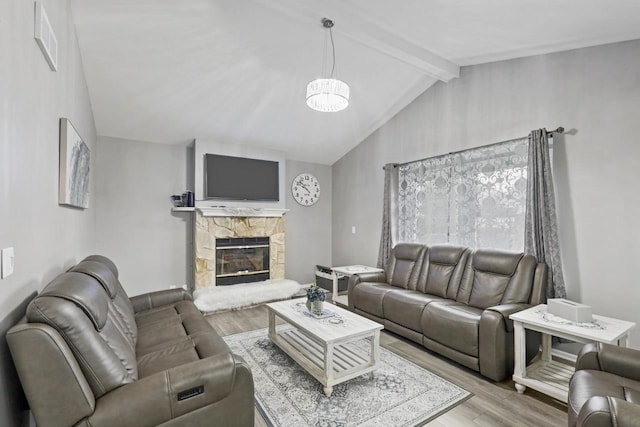 living room with a stone fireplace, wood finished floors, visible vents, and vaulted ceiling with beams