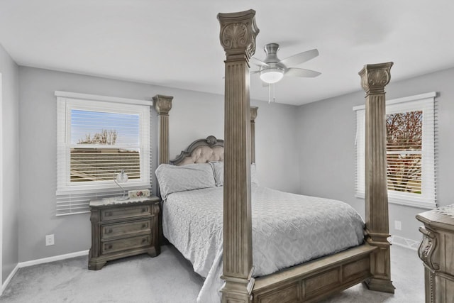 carpeted bedroom with a ceiling fan, multiple windows, and baseboards
