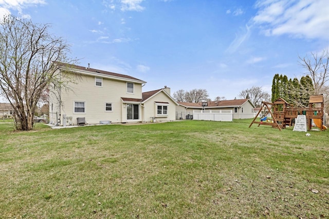 back of house with fence, a chimney, a yard, and a playground