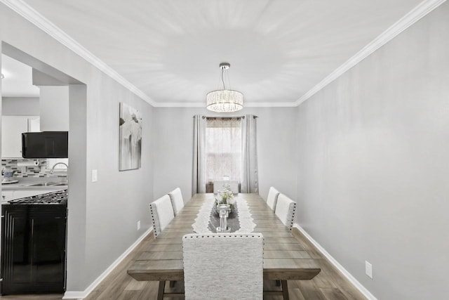dining area featuring crown molding, a notable chandelier, baseboards, and light wood-style floors