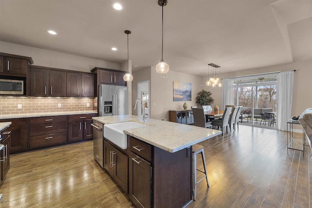 402 Burnt Sienna Dr, Middleton, WI 53562 - kitchen with a sink, decorative backsplash, a kitchen breakfast bar, dark brown cabinetry, and appliances with stainless steel finishes