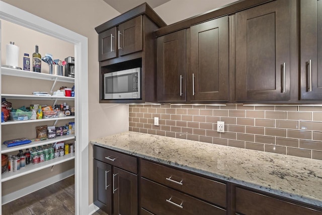 402 Burnt Sienna Dr, Middleton, WI 53562 - kitchen featuring light stone counters, dark wood-style flooring, stainless steel microwave, and dark brown cabinetry