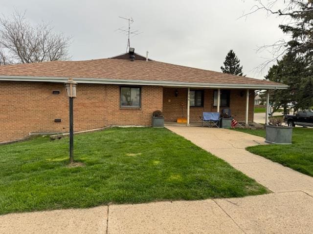 back of property with a lawn, roof with shingles, covered porch, and brick siding