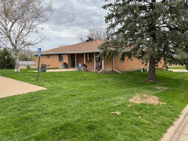 rear view of house with a yard, covered porch, and brick siding