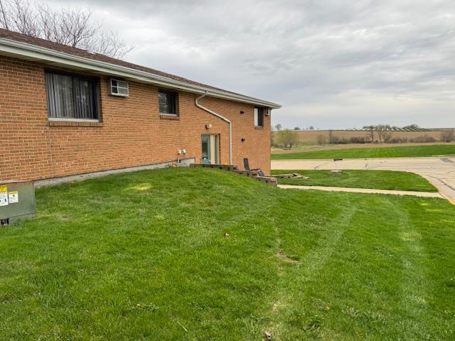 back of property featuring a lawn and brick siding