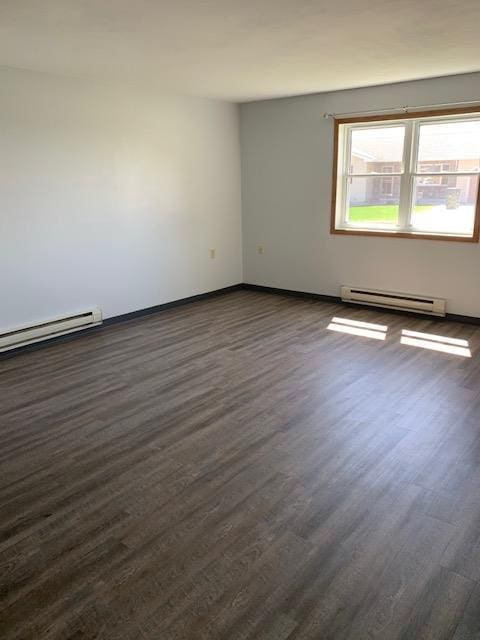 unfurnished room with dark wood-style flooring, baseboard heating, and baseboards