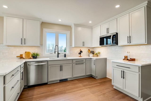 2352 Ryan Ave, Plymouth, WI 53073 - kitchen featuring backsplash, light wood finished floors, a sink, and appliances with stainless steel finishes
