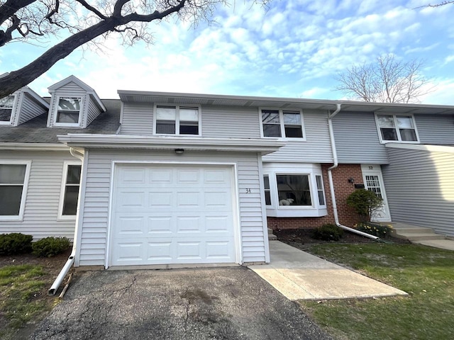 view of property featuring an attached garage and aphalt driveway