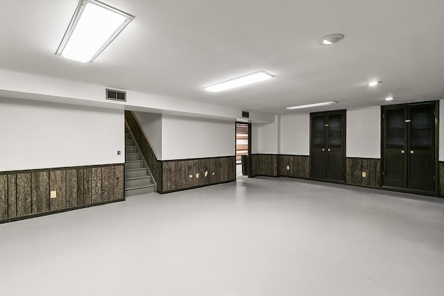 unfurnished room with wainscoting, recessed lighting, finished concrete floors, visible vents, and stairway