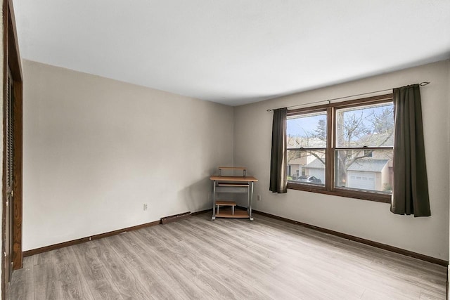 spare room featuring baseboards and light wood-type flooring