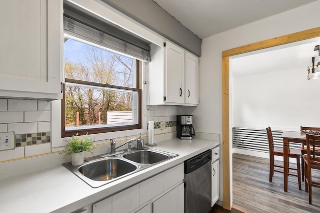 kitchen featuring light countertops, white cabinets, tasteful backsplash, a sink, and dishwasher