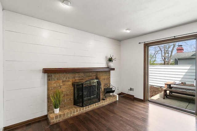 unfurnished living room with baseboards, wood finished floors, and a fireplace