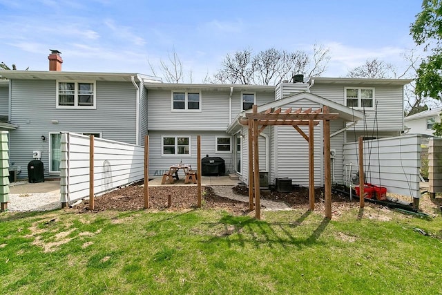 back of house with fence, a pergola, a patio, a chimney, and a yard