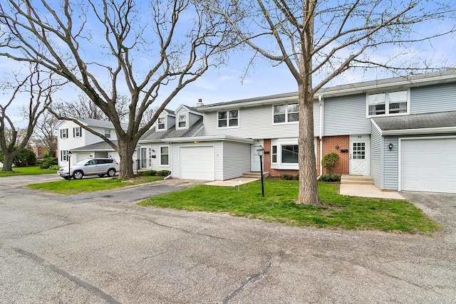 view of property with a garage, a front lawn, aphalt driveway, brick siding, and a residential view